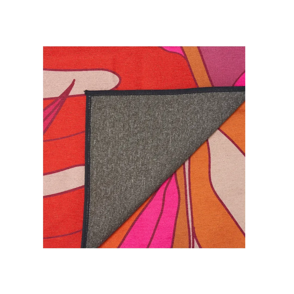Owala towel in Tropic Like It's Hot, back detail showing the corner folded over to reveal grey microfiber backing against a pink, red, and orange print